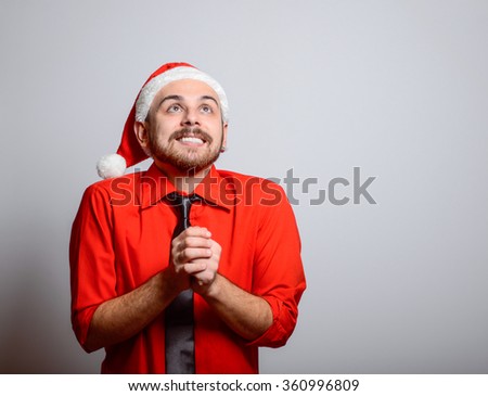 Business man praying. Winter, corporate party, Christmas hat isolated portrait of a man on a gray background, studio photo.
