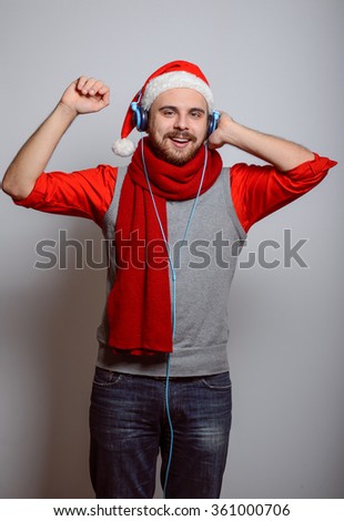 Business man listening to music with big headphones to the phone. Corporate party, Christmas hat isolated portrait of a man on a gray background, studio photo.