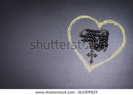 in the picture a rosary iron at the center of a heart drawn with a crayon and copy space in the left side.