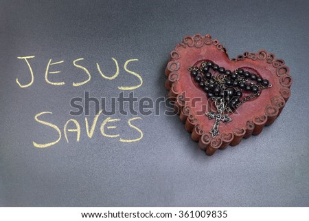In the picture a rosary iron placed over a heart of red wax, on the left side the inscription "Jesus Saves" made with a crayon.
