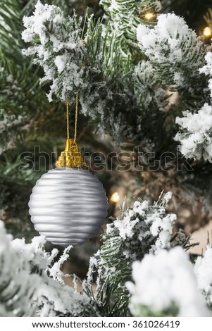 Snowy fir tree branches with flash lights and one silver ball