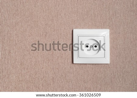 White standard electric socket on a wall as a background