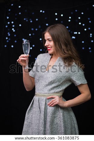 Beautiful woman with a glass of champagne on a black background with bokeh