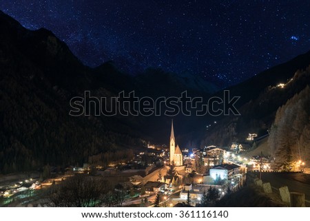 Night town Heiligenblut, surrounded by Alps Mountains with starry sky, Austria, Europe