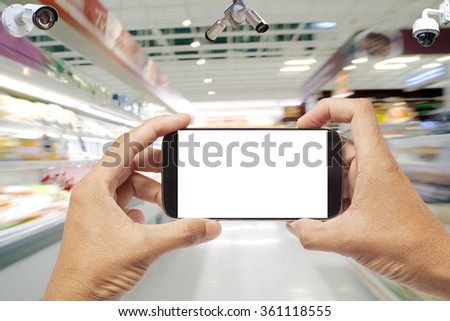Hand using smartphone photographed and CCTV system security in supermarket ,Do not take pictures in the supermarket concept