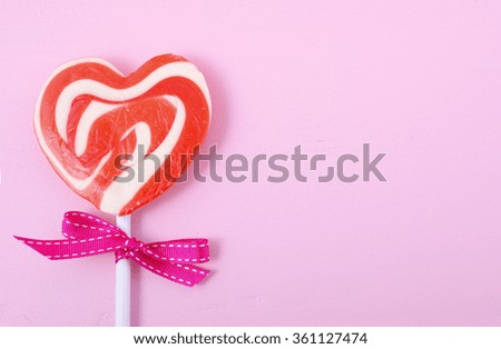 Happy Valentines Day candy with red heart shape lollipop on pink wood background with copy space.