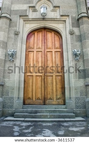 Wooden doors in ancient castle. On each side doors iron holders for torches and lantern. Ancient ornament on walls