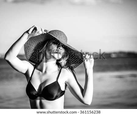 Young attractive girl in a hat on the beach. The concept of summer vacation. Black and white photography. Shooting in low key.