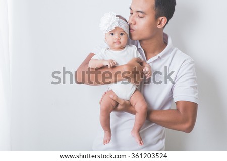 A portrait of a Young Asian father holding and kissing his adorable baby on white background