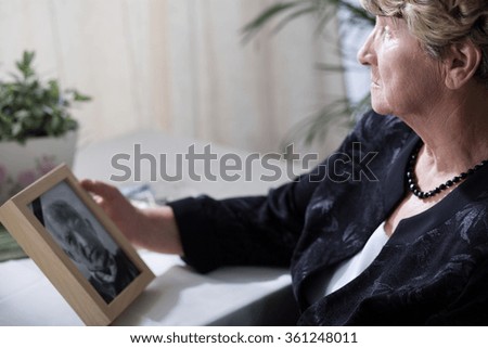 Photo of senior widow reminiscing her dead husband Royalty-Free Stock Photo #361248011