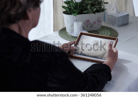 Picture of lonely aged female holding photo from past Royalty-Free Stock Photo #361248056