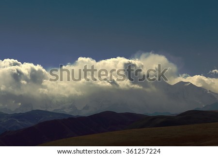 Clouds cover mounts Shisha Pangma-Gosainthan-Crest above the grassy plains 8013 ms.+Yebokangal Ri 7365 ms.to the right. From Tong La pass at 5120 ms.-Friendship Highway between Tingri and Nyalam-Tibet