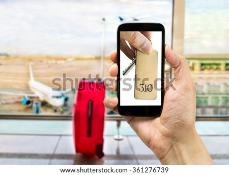 hand holding a smart phone with a picture of hand holding the key of hotel at the airport lounge