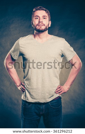 Portrait of handsome fashionable man in blank shirt with empty copy space. Young guy in studio on black. Casual fashion advertisement. Instagram filter.