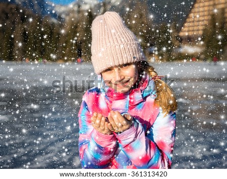 Happy girl in winter clothes enjoying winter holidays outdoors