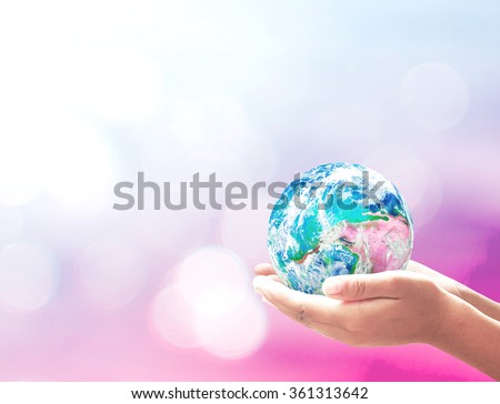 World environment day concept: Human hands holding earth globe over blurred pink nature pattern background. Elements of this image furnished by NASA