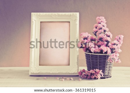 The White vintage photo frame with sweet statice flower in basket with blank wooden label on red pink background and wooden table , romance concept