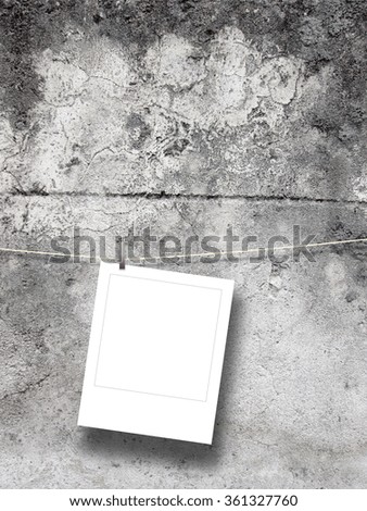Close-up of one blank square instant photo frame with peg on weathered concrete wall background