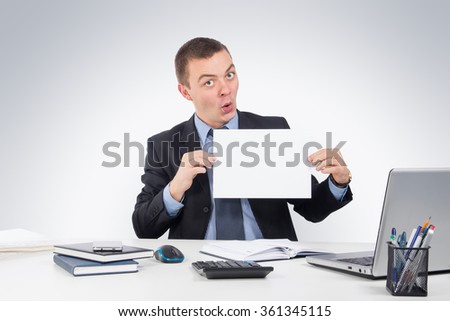 Office,technology, finances, internet, business, success and people concept-Young businessman holds up a blank peice of paper with copyspace for your text and a smile
