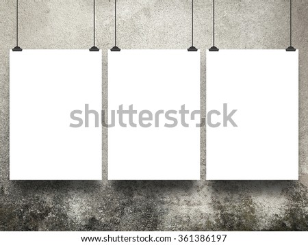 Close-up of three hanged paper sheets with clips on weathered concrete wall background