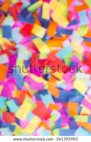 Brightly colored paper confetti background in defocus featuring red, yellow, blue, green, orange, and bright pink carnival colors