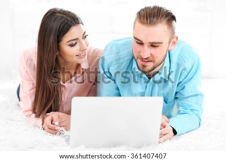 Happy couple lying on the floor and working on laptop