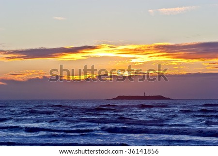 Beautiful sunset over Pacific Ocean with island and lighthouse silhouette pictured on Ruby Beach, Washington, USA