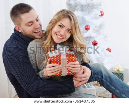 smiling young couple near Christmas tree with gift. happy holiday concept