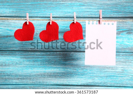Blank paper hanging on rope on blue wooden background
