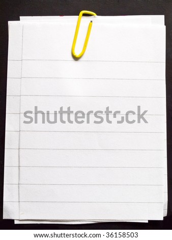 papers with yellow paper clip isolated on black