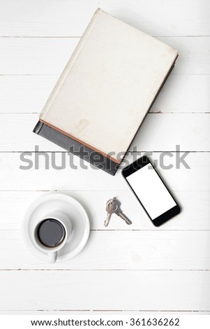coffee cup with phone,key and stack of book on white wood table