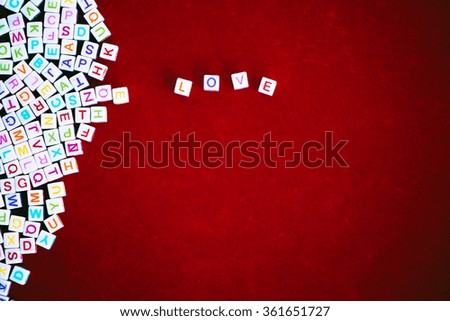 Caption word love with heart shape on red background. Love inscription from plastic alphabet letter. Valentine's day card.
