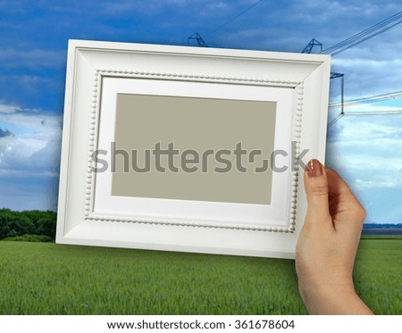 Wooden frame in beautiful woman hands on the background Fields and Sky