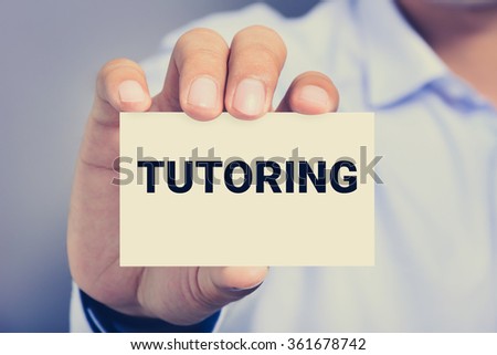 TUTORING word on the card held by a man hand, vintage tone