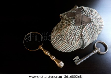Sherlock Holmes Deerstalker Hat, Old Key And Vintage  Magnifying Glass On The Black Wooden Table Background. Overhead View.  Investigation Concept.