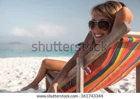 Young lady relaxing in the chair on a tropical beach with white sand