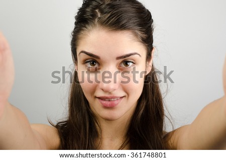 Happy cute woman making selfie over gray background. Looking at camera