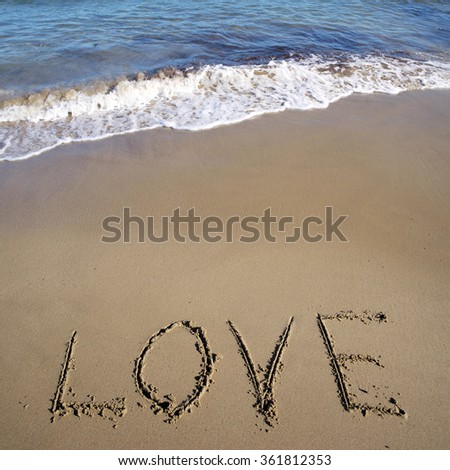Photo closeup of word love written on beautiful wet beige beach sea marine grained sand against blue waves with splashes white spindrifts running on seashore on seascape background, square picture