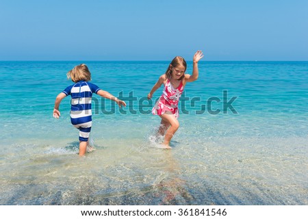 Two kids having fun on summer vacation, playing in the sea, image taken in Tropea, Calabria, Italy
