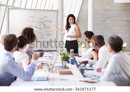 Hispanic Businesswoman Leading Meeting At Boardroom Table