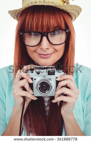 Portrait of a smiling hipster woman holding retro camera against white background