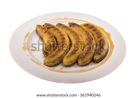 fried bananas with honey on a plate on the isolated background