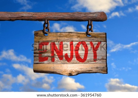 Enjoy motivational phrase sign on old wood with blurred background