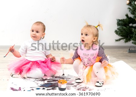 Children, little girls paint colors near a Christmas tree