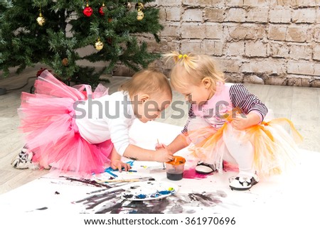 Children, little girls paint colors near a Christmas tree