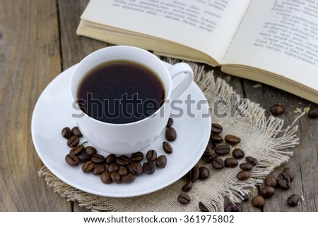 Top view of white cup of coffee with old book on wooden background