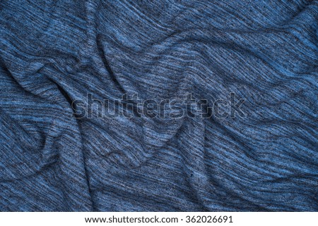 Creased knitted blue striped cloth material fragment as a background texture composition