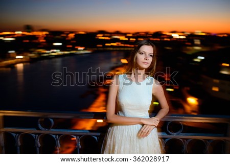 beautiful woman stands on a bridge at sunset