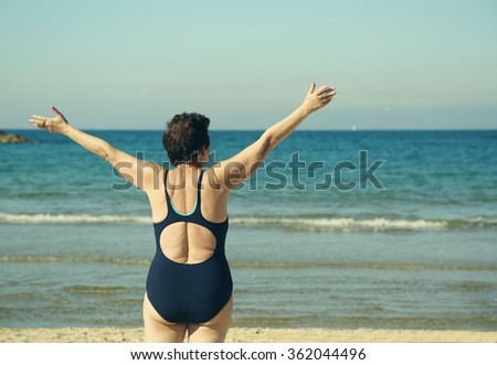  Senior woman standing with open arms over sky background