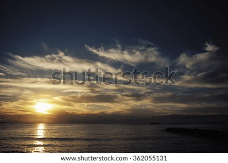 Photo long shot of beautiful marine calm evening with pier dark silhouette of yacht floating in sea against amazing sunset and low white clouds on horizon on seascape background, horizontal picture